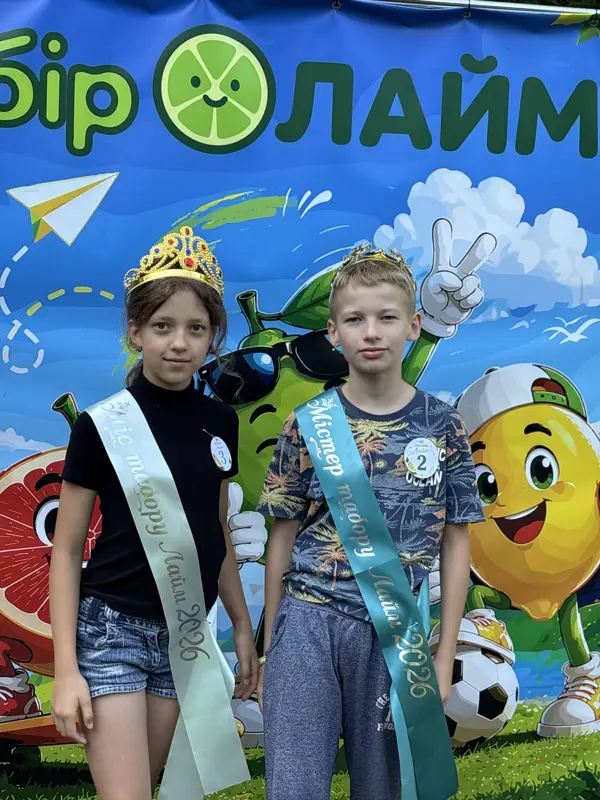 Діти з короною та стрічкою на фоні банера табору
